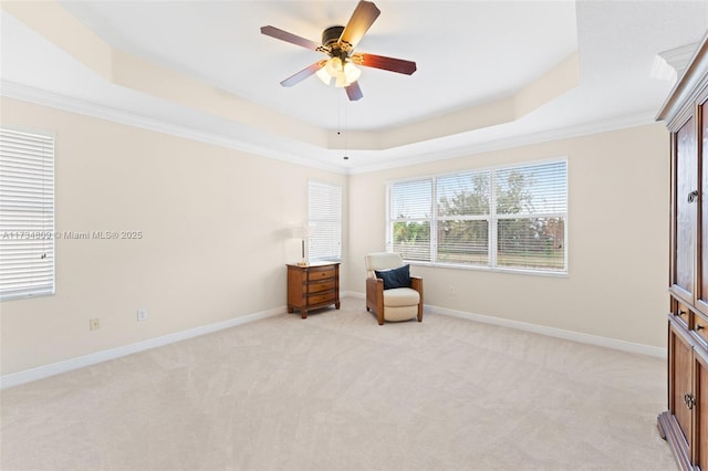 unfurnished room featuring baseboards, a raised ceiling, light colored carpet, ceiling fan, and crown molding