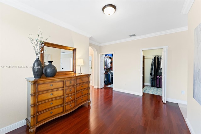 bedroom with arched walkways, ornamental molding, dark wood-type flooring, a spacious closet, and a closet