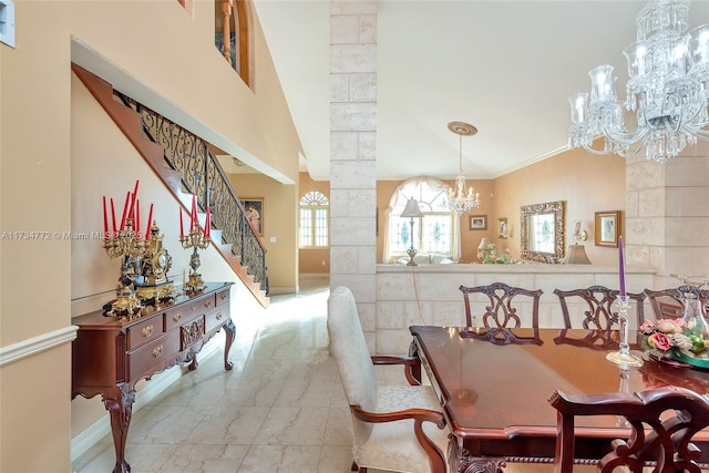 dining space featuring a high ceiling, crown molding, decorative columns, and an inviting chandelier