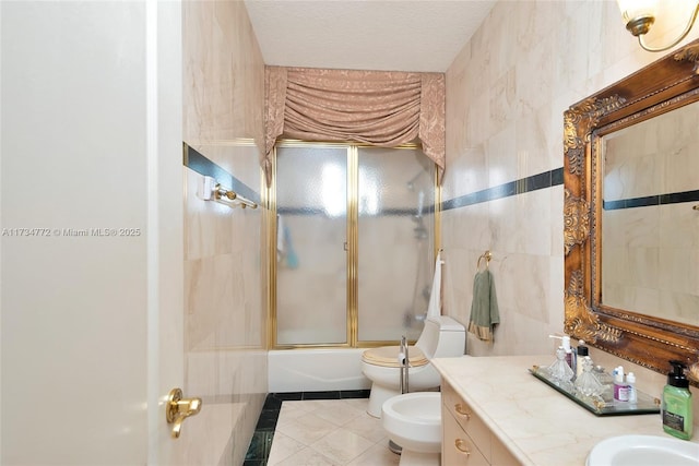 full bathroom with combined bath / shower with glass door, tile walls, vanity, a bidet, and tile patterned floors