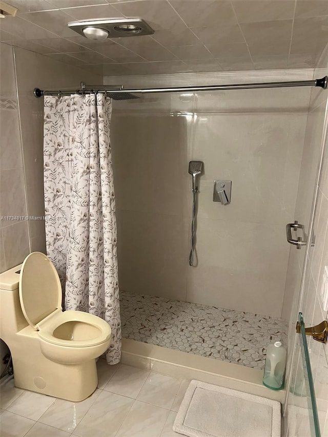 bathroom with tile patterned floors, toilet, and curtained shower