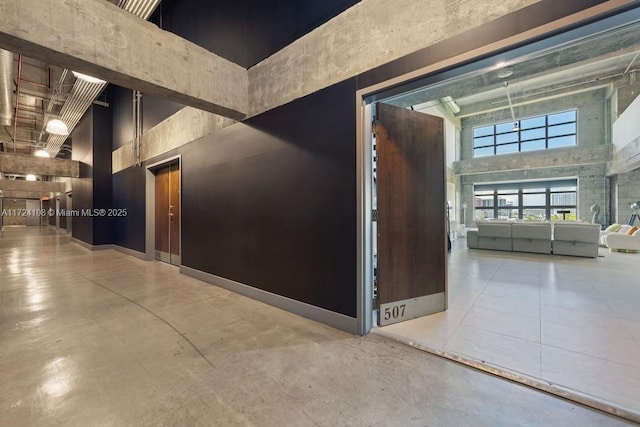 hallway featuring a towering ceiling and concrete floors