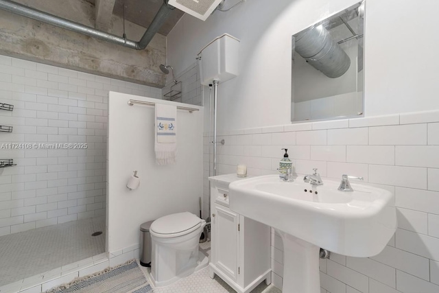 bathroom featuring tiled shower, tile patterned floors, toilet, and tile walls