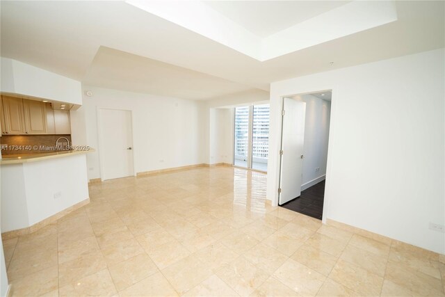 unfurnished room featuring sink and a tray ceiling