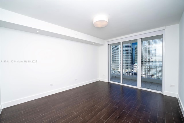 empty room featuring floor to ceiling windows and dark hardwood / wood-style flooring