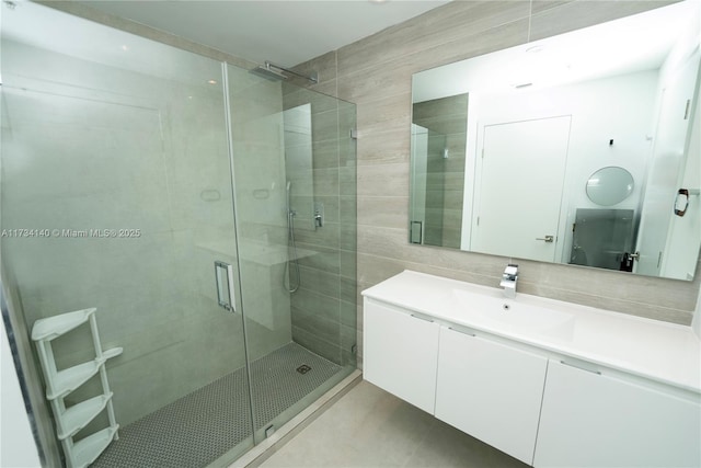 bathroom featuring tile walls, vanity, a shower with door, tile patterned flooring, and backsplash