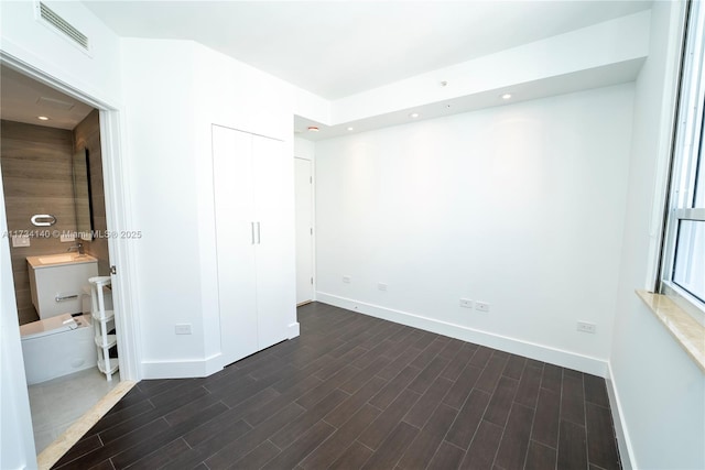 unfurnished bedroom with dark wood-type flooring, sink, and a closet