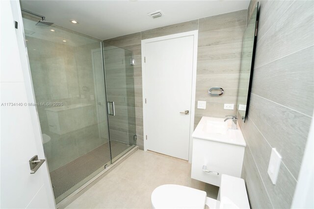 bathroom featuring vanity, an enclosed shower, and tile walls