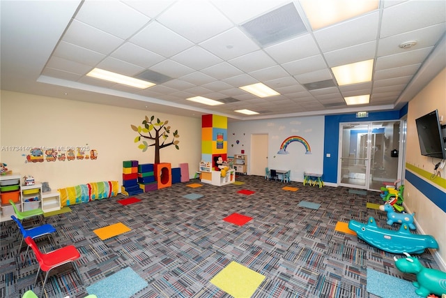 recreation room featuring a paneled ceiling and carpet