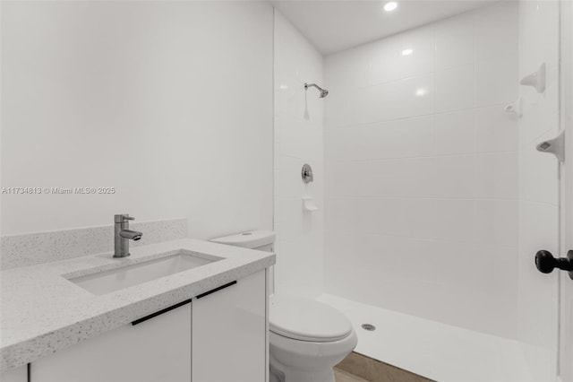 bathroom with vanity, a tile shower, and toilet