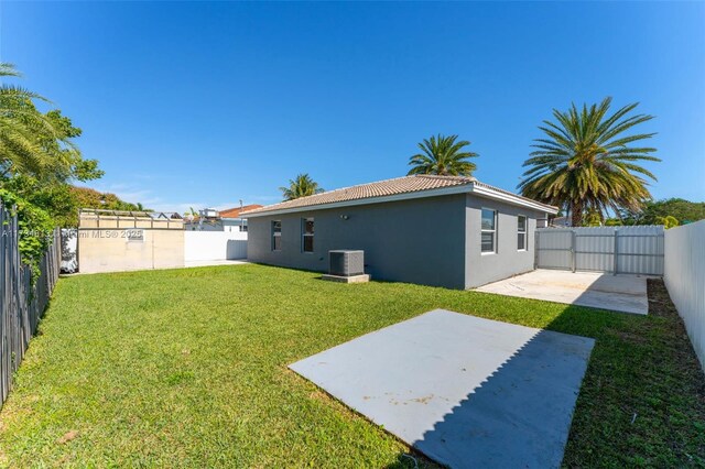 back of house featuring central AC unit, a patio area, and a lawn