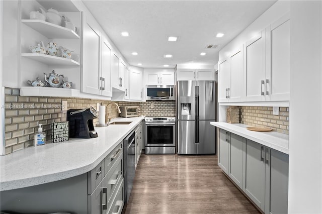 kitchen with sink, appliances with stainless steel finishes, dark hardwood / wood-style floors, light stone countertops, and white cabinets