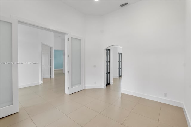 tiled spare room with a towering ceiling