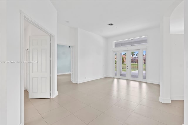 spare room featuring french doors and light tile patterned floors