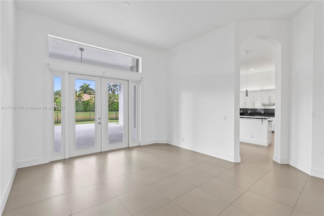 spare room featuring light tile patterned floors and french doors