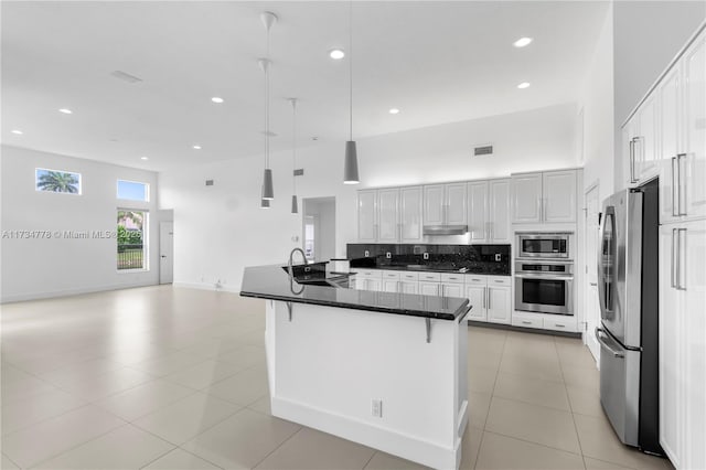 kitchen featuring decorative light fixtures, appliances with stainless steel finishes, a kitchen breakfast bar, white cabinets, and backsplash