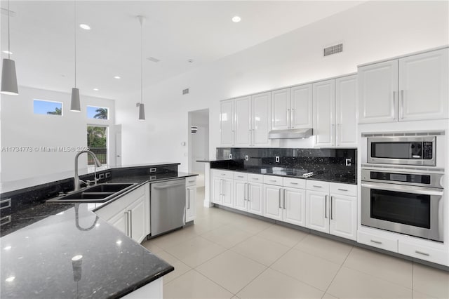 kitchen featuring sink, white cabinetry, appliances with stainless steel finishes, pendant lighting, and dark stone counters