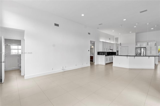 unfurnished living room with a towering ceiling and light tile patterned flooring