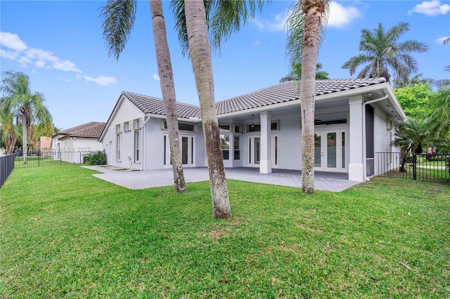 rear view of property with french doors, ceiling fan, a patio, and a lawn