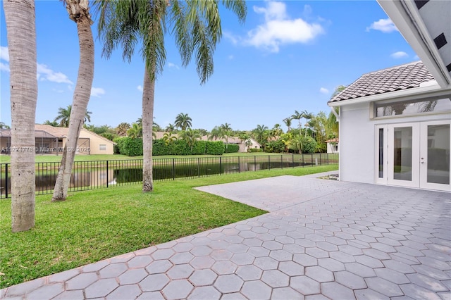 view of yard with a patio area, french doors, and a water view