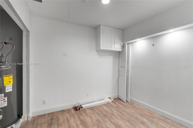 empty room with electric water heater and light wood-type flooring