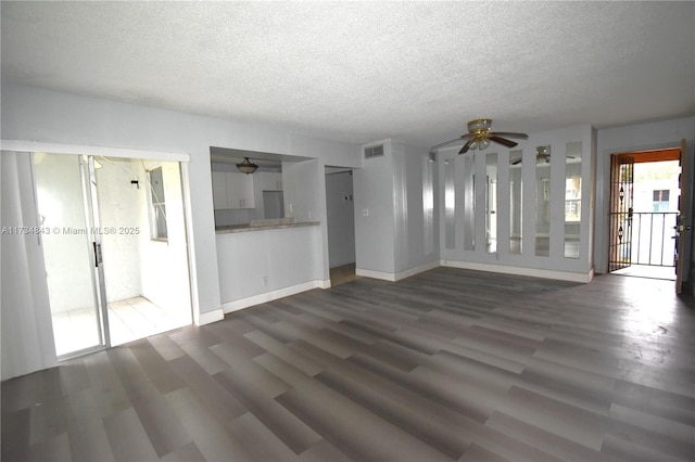 unfurnished living room featuring ceiling fan, dark hardwood / wood-style floors, and a textured ceiling