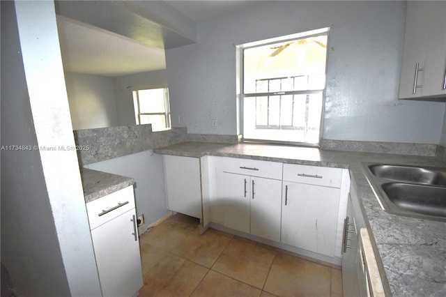 kitchen with light tile patterned floors, sink, and white cabinets