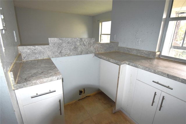 kitchen featuring light tile patterned flooring, a wealth of natural light, and white cabinets