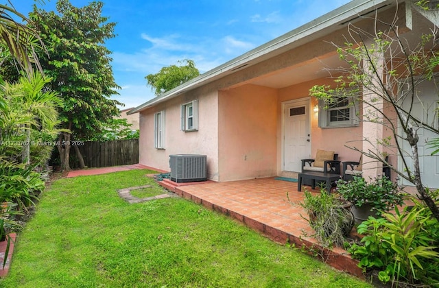 rear view of house with cooling unit, a patio area, and a lawn