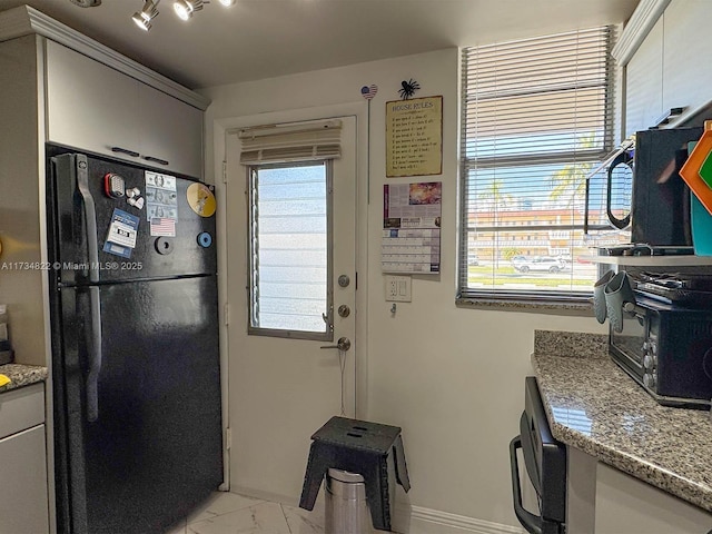 kitchen with black refrigerator and light stone countertops