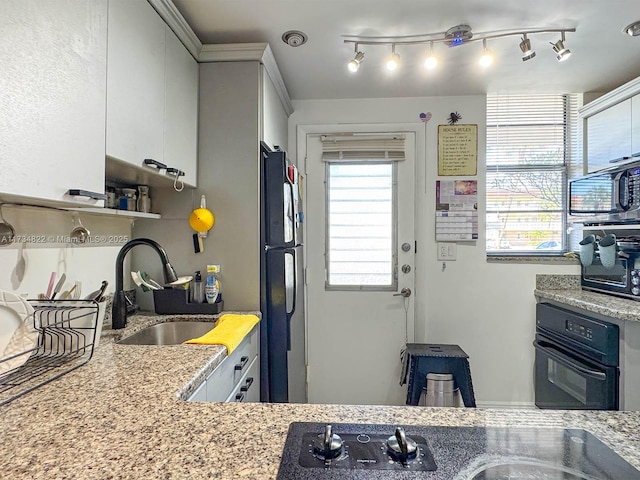 kitchen featuring white cabinetry, sink, black appliances, and light stone countertops