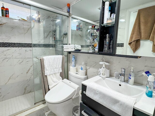 bathroom featuring tasteful backsplash, vanity, a shower with shower door, and toilet