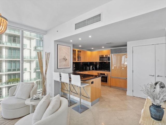 kitchen with a breakfast bar, sink, light brown cabinets, stainless steel appliances, and decorative backsplash