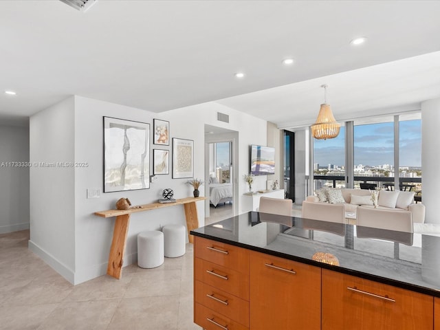 kitchen featuring expansive windows, pendant lighting, dark stone countertops, and light tile patterned floors