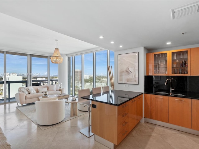 kitchen with a healthy amount of sunlight, floor to ceiling windows, kitchen peninsula, and sink