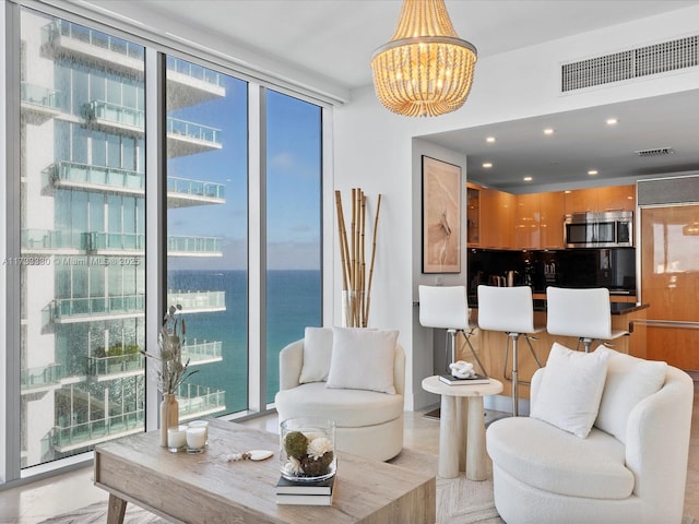 living room featuring expansive windows, a chandelier, and a water view