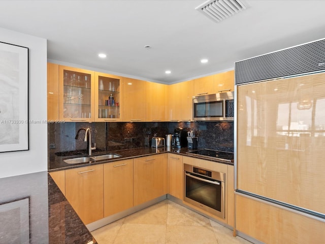 kitchen with sink, light brown cabinets, appliances with stainless steel finishes, dark stone counters, and backsplash