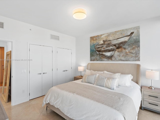 bedroom featuring two closets and light tile patterned floors