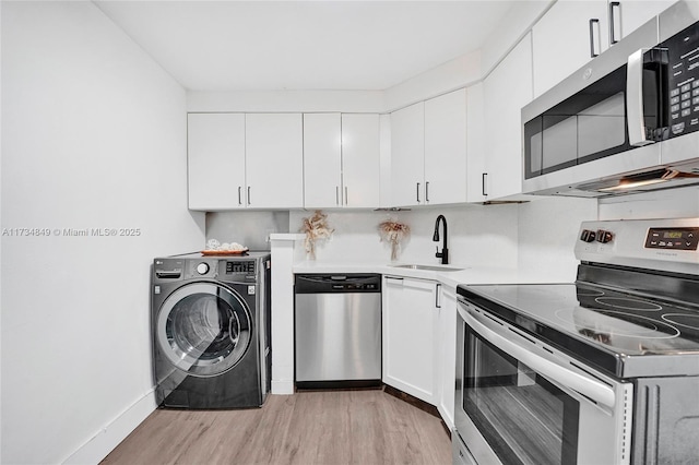 kitchen featuring sink, appliances with stainless steel finishes, white cabinetry, light hardwood / wood-style floors, and washer / dryer