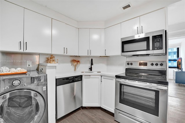 kitchen featuring washer / dryer, sink, tasteful backsplash, appliances with stainless steel finishes, and white cabinets