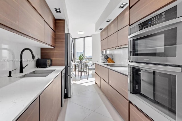 kitchen featuring stainless steel appliances, floor to ceiling windows, sink, and light tile patterned floors