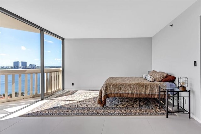 bedroom with tile patterned flooring, floor to ceiling windows, and a water view