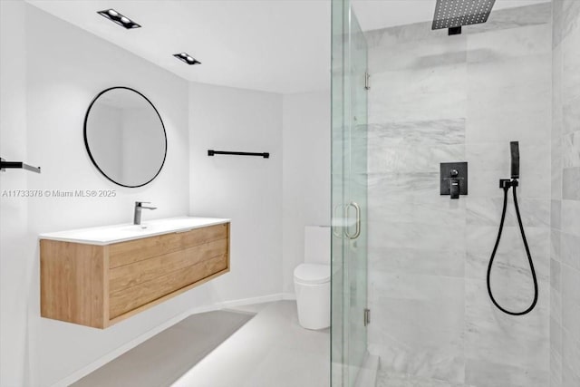 bathroom featuring vanity, a shower with shower door, and toilet