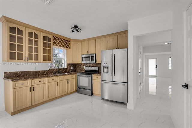 kitchen featuring sink, light brown cabinets, dark stone counters, and appliances with stainless steel finishes