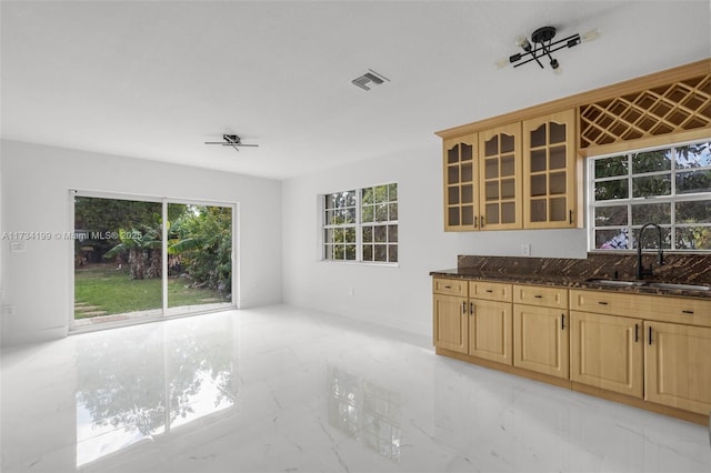 kitchen with dark stone countertops, sink, and ceiling fan