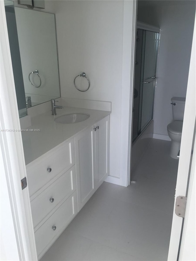 bathroom featuring vanity, toilet, a shower with door, and tile patterned flooring