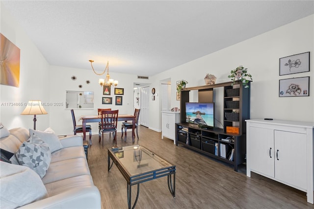 living room with dark hardwood / wood-style flooring, a notable chandelier, and a textured ceiling