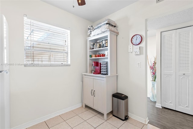 interior space with light tile patterned floors, ceiling fan, baseboards, and a closet