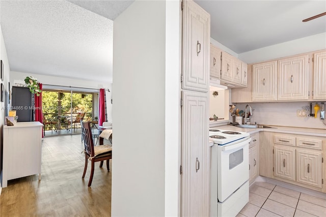 kitchen featuring light tile patterned floors, white range with electric cooktop, light countertops, a sink, and a textured ceiling