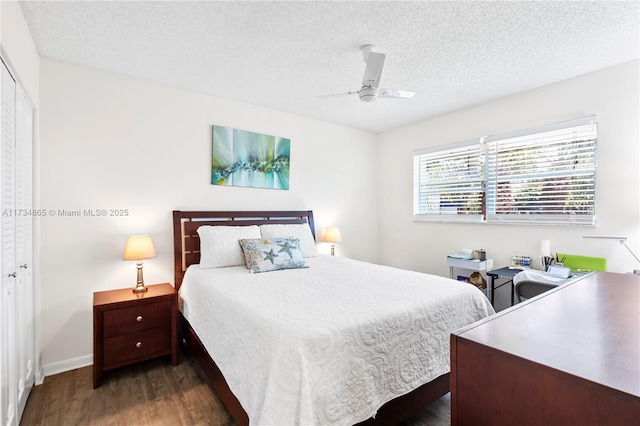 bedroom featuring baseboards, ceiling fan, dark wood-type flooring, a textured ceiling, and a closet